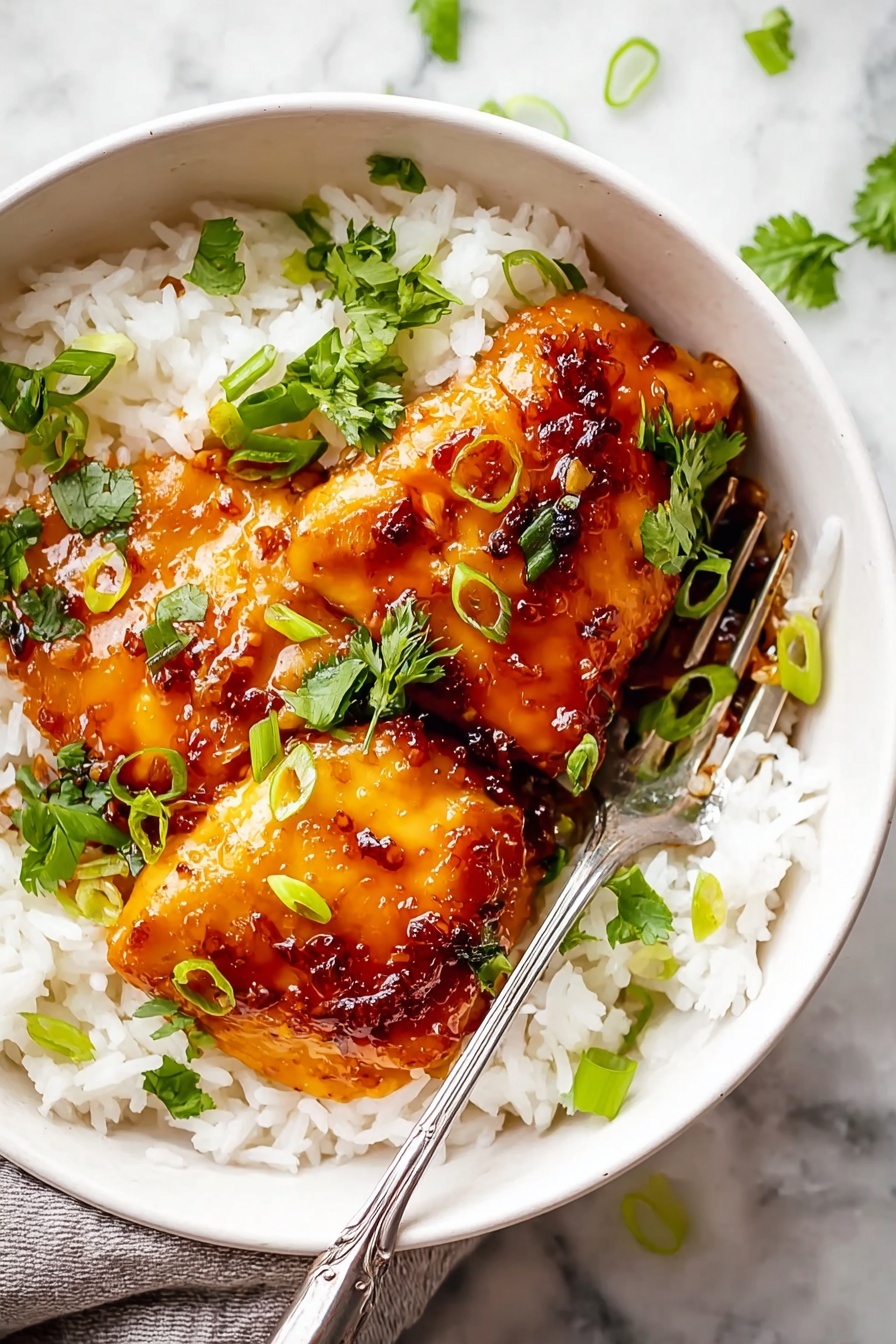 A white bowl sits on a white marbled surface, filled with a base layer of fluffy, white rice. On top, there are two pieces of golden-brown glazed chicken with a shiny, sticky sauce that has a rich, amber color. Bright green sliced scallions and small cilantro leaves are scattered over the chicken and rice. A silver fork rests inside the bowl on the left side, touching the rice. The image highlights the contrast between the white rice and the warm tones of the chicken and sauce, with fresh green garnish adding a pop of color. photo taken with an iphone --ar 2:3 --v 7