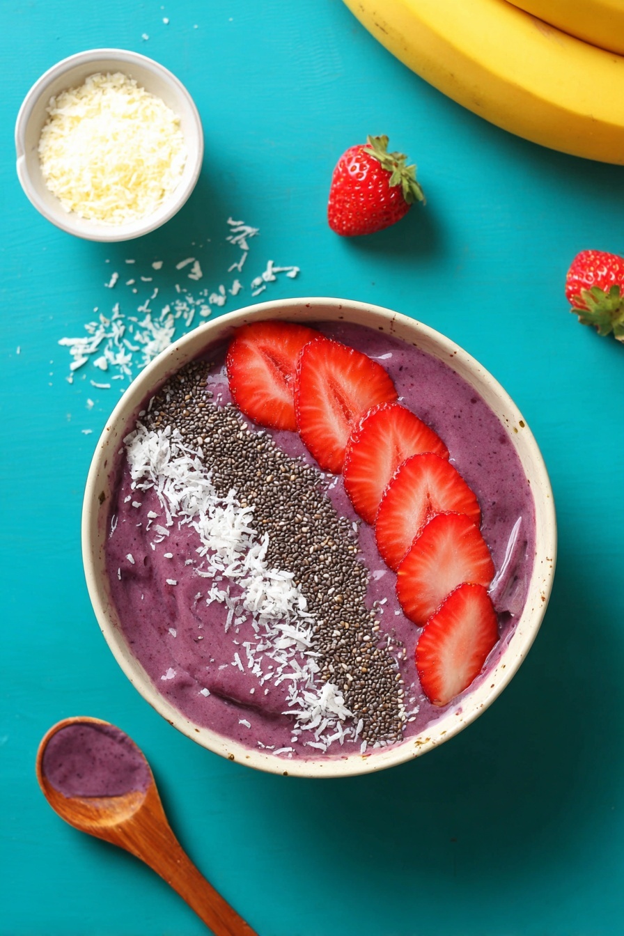 A white bowl filled with a thick purple smoothie base is topped with three clear sections of toppings. On the right side, five bright red strawberry slices are neatly placed in a row. Next to the strawberries in the middle, there is a line of small black chia seeds. On the left side, there is a scattering of white shredded coconut flakes. The bowl sits on a bright turquoise surface, with some strawberry slices, a small white bowl of shredded coconut, a wooden spoon with a dollop of purple smoothie, and a yellow banana visible around it. photo taken with an iphone --ar 2:3 --v 7