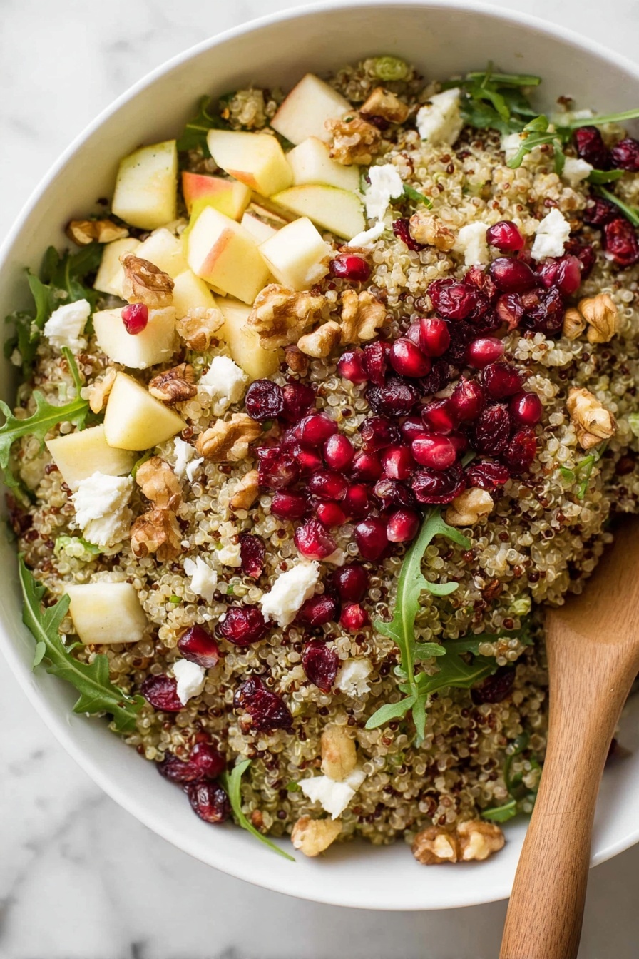 A white bowl holds a colorful quinoa salad with several layers visible: at the base is light brown quinoa, mixed with small pieces of white cheese, green arugula leaves, red pomegranate seeds, small chunks of pale yellow apple, and scattered walnuts. The textures vary from fluffy quinoa to juicy fruit and crunchy nuts. A wooden spoon rests inside the bowl, partially covered by the salad. Around the bowl on a white marbled surface are scattered pomegranate seeds, green arugula leaves, quinoa grains, and parts of a pomegranate fruit, with a soft white cloth partially visible on the left side. photo taken with an iphone --ar 2:3 --v 7