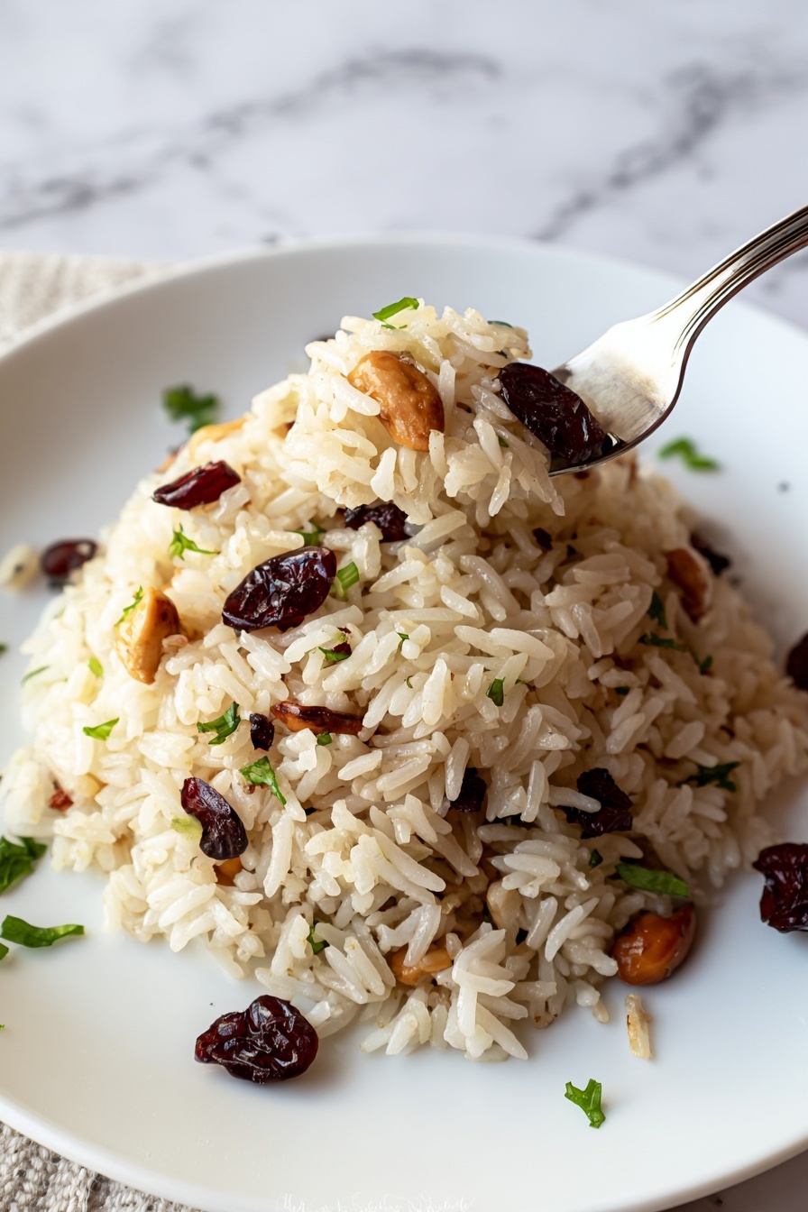A round white plate holds a mound of light brown rice pilaf mixed with dark red cranberries and light tan almond slices. Small green herb pieces are scattered on top and around the base of the rice. A metal fork rests next to the pilaf on the plate. The plate is set on a neutral woven fabric surface with red leaves blurred in the background, all placed on a white marbled texture. photo taken with an iphone --ar 2:3 --v 7