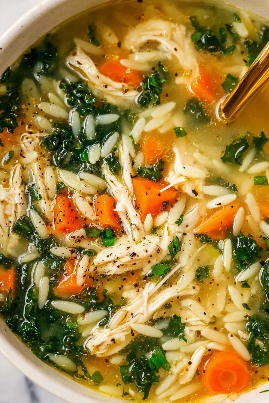 A white bowl of chicken soup with visible shredded white chicken pieces, bright orange carrot slices, green leafy kale, small white pasta shapes, and light green celery pieces floating in a clear broth, topped with sprinkled black pepper and chopped parsley, a golden spoon standing in the bowl, placed on a white marbled surface next to a small white bowl of chopped greens and a blue and white striped cloth napkin photo taken with an iphone --ar 2:3 --v 7