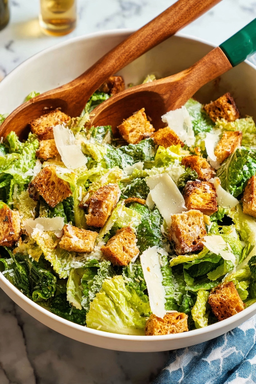 A large white bowl filled with a Caesar salad, showing three main layers: the bottom layer is bright green Romaine lettuce with a fresh, crisp texture; the middle layer has golden brown croutons with a crunchy surface; the top layer is scattered thin, off-white cheese shavings that sit lightly on top. Two wooden salad tongs with green painted handles rest inside the bowl, positioned slightly diagonally. The scene includes a white plate stacked with three vintage forks on the left upper side and a glass being filled with pale yellow white wine from a bottle at the upper right corner. The background is a white marbled surface with a folded blue napkin featuring white heart shapes placed near the glass. Photo taken with an iphone --ar 2:3 --v 7