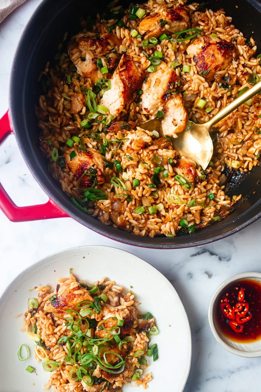 A black pot with red handles holds a dish of small brown rice grains mixed with golden-brown cooked chicken pieces. The chicken is sprinkled with black sesame seeds and small green herbs and scallions, adding fresh bright green touches. A golden spoon is scooping some of the rice and herbs inside the pot. Next to it, a white plate shows a serving of the same dish with the chicken on top of the rice and garnished with green scallion curls and parsley. A small white bowl nearby contains a dark red oily sauce with visible chili seeds and spices. All items rest on a white marbled surface. photo taken with an iphone --ar 2:3 --v 7