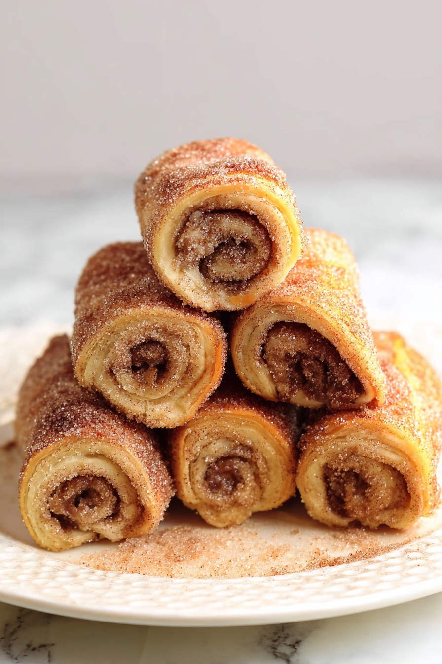 The image shows six rolled pastries stacked in a pyramid shape on a white plate with a textured pattern. Each roll has a golden-brown outer layer coated with a sugary cinnamon mixture that sparkles in the light. The inside of the rolls reveals a spiral pattern of a darker cinnamon filling that contrasts with the lighter dough. The plate sits on a white marbled surface, making the warm tones of the rolls stand out. Photo taken with an iphone --ar 2:3 --v 7