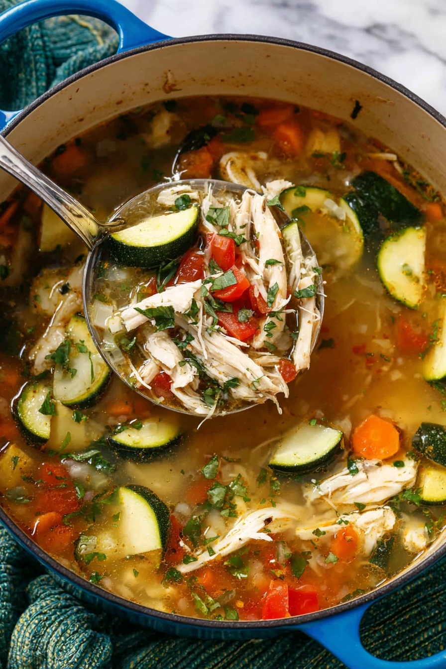 A blue pot filled with a clear broth soup showing four main layers: the light brown broth base, scattered pieces of green zucchini with dark green skin, pale shredded chicken strips, and small diced vegetables like orange carrots and red tomatoes, all topped with chopped green herbs. A large silver spoon lifts a mix of shredded chicken, zucchini pieces, and diced carrots above the soup, revealing the rich soup layers beneath. The pot is set on a white marbled surface with a textured green cloth underneath. Photo taken with an iphone --ar 2:3 --v 7