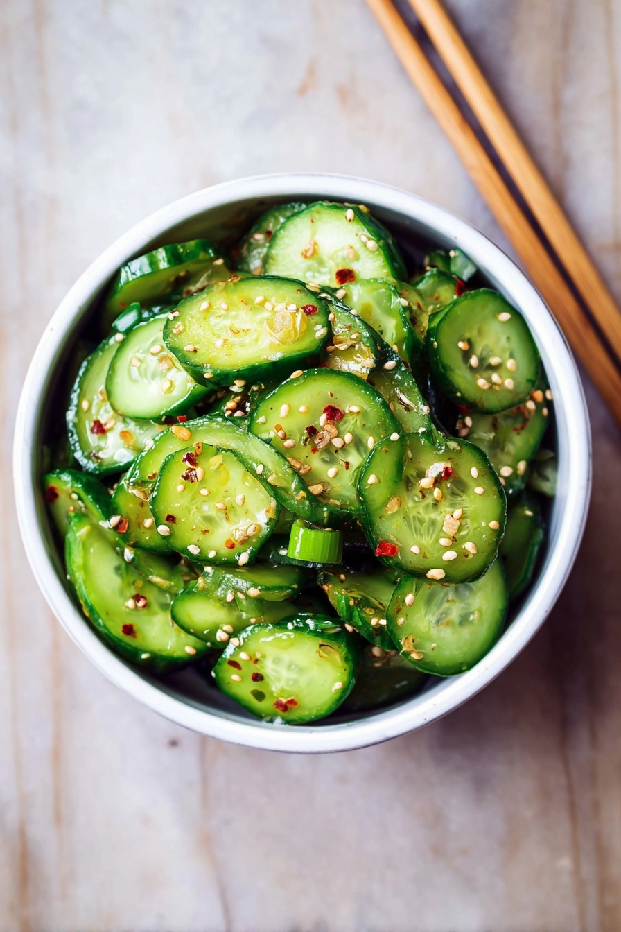 A white bowl filled with many round cucumber slices stacked loosely, each slice is bright green with darker skin edges, and the slices are coated with small sesame seeds and tiny pieces of green onion scattered throughout. The cucumbers look fresh and lightly shiny as if dressed with a light sauce. The bowl sits on a white marbled surface with a pair of wooden chopsticks placed above it. Photo taken with an iphone --ar 2:3 --v 7
