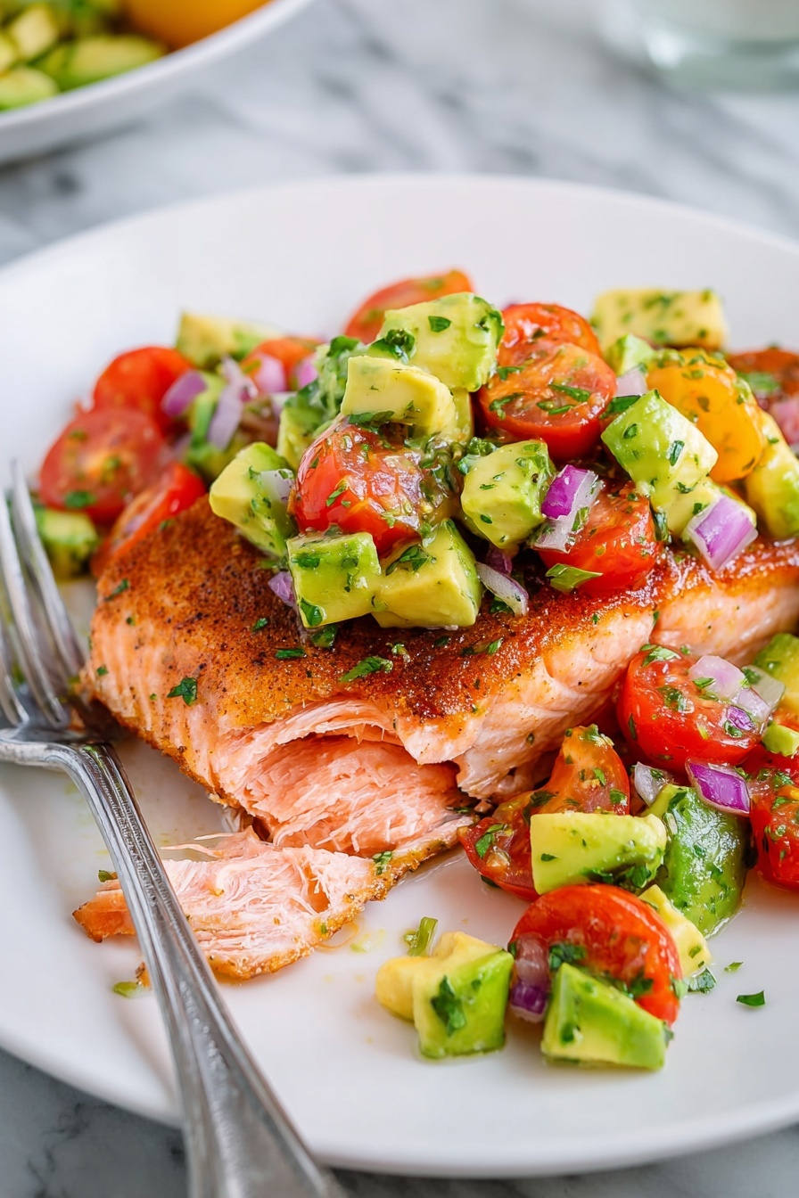 A white plate holds a piece of cooked salmon with a golden-brown crispy skin on the outside and tender, flaky pink flesh inside. On top of the salmon is a chunky mix of diced avocado, bright red cherry tomatoes, and small pieces of purple onion with green herbs sprinkled throughout. The salad looks fresh and colorful with a mix of green, red, and purple, contrasted by the warm salmon below. A silver fork lies on the plate beside the salmon and salad. The scene is set on a smooth white marbled surface. photo taken with an iphone --ar 2:3 --v 7