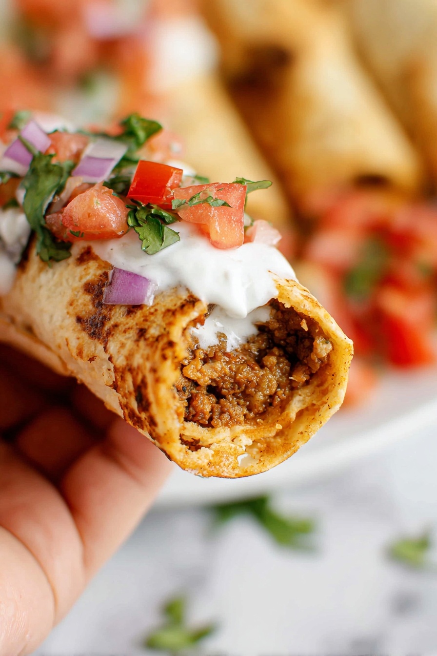 A close-up of a folded white tortilla wrap filled with cooked brown ground meat, held by a woman's hand. The wrap has a slightly toasted, soft texture with visible browned spots. On top of the wrap is a layer of white sour cream, then a fresh topping of chopped red tomatoes, small purple onion pieces, and green cilantro leaves. In the blurred background, there are more wraps with similar toppings on a white plate, all set on a white marbled surface. photo taken with an iphone --ar 2:3 --v 7